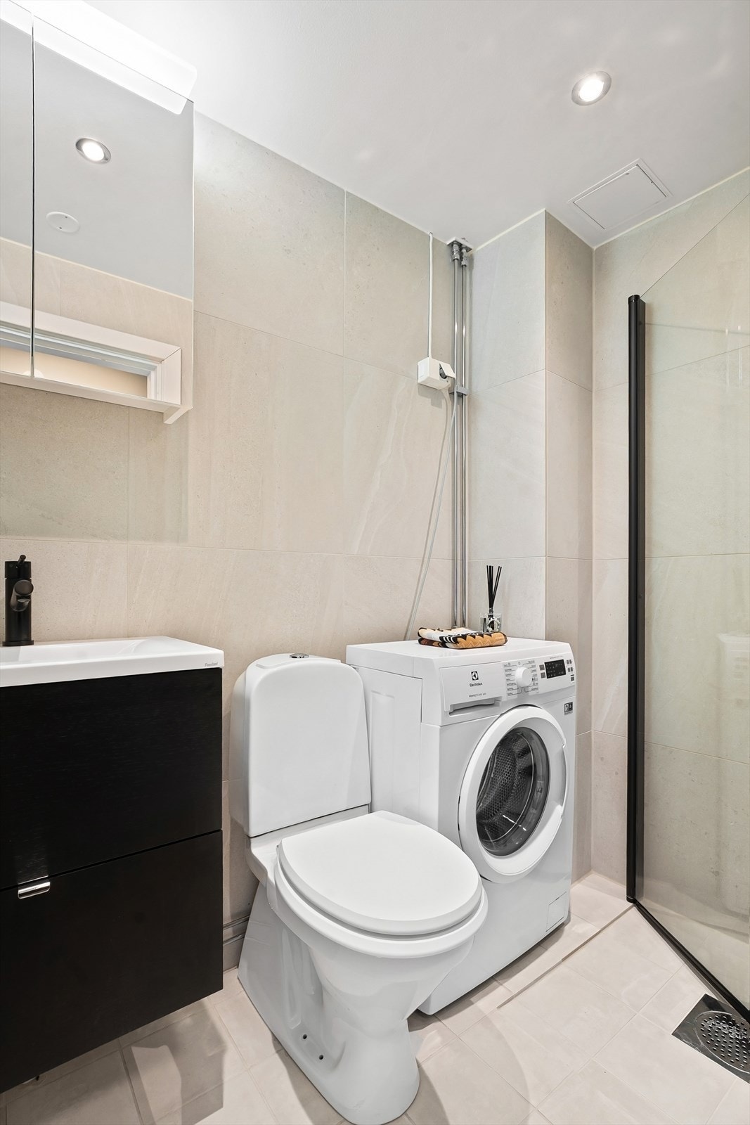 Badet er utstyrt med vegghengt servantinnredning med dører, ovenpåliggende servant med ett-greps armatur (2020), speil med overlys og gulvstående toalett. Videre er det dusjhjørne med dører og vegghengt dusjarmatur. Galleribilde