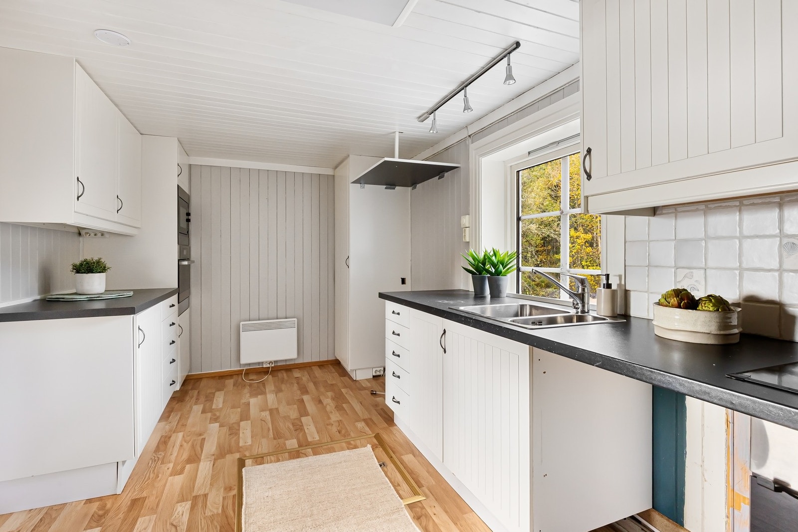 Lyst og tidløst kjøkken med profilerte fronter, fliser over benk og god arbeidsplass Galleribilde