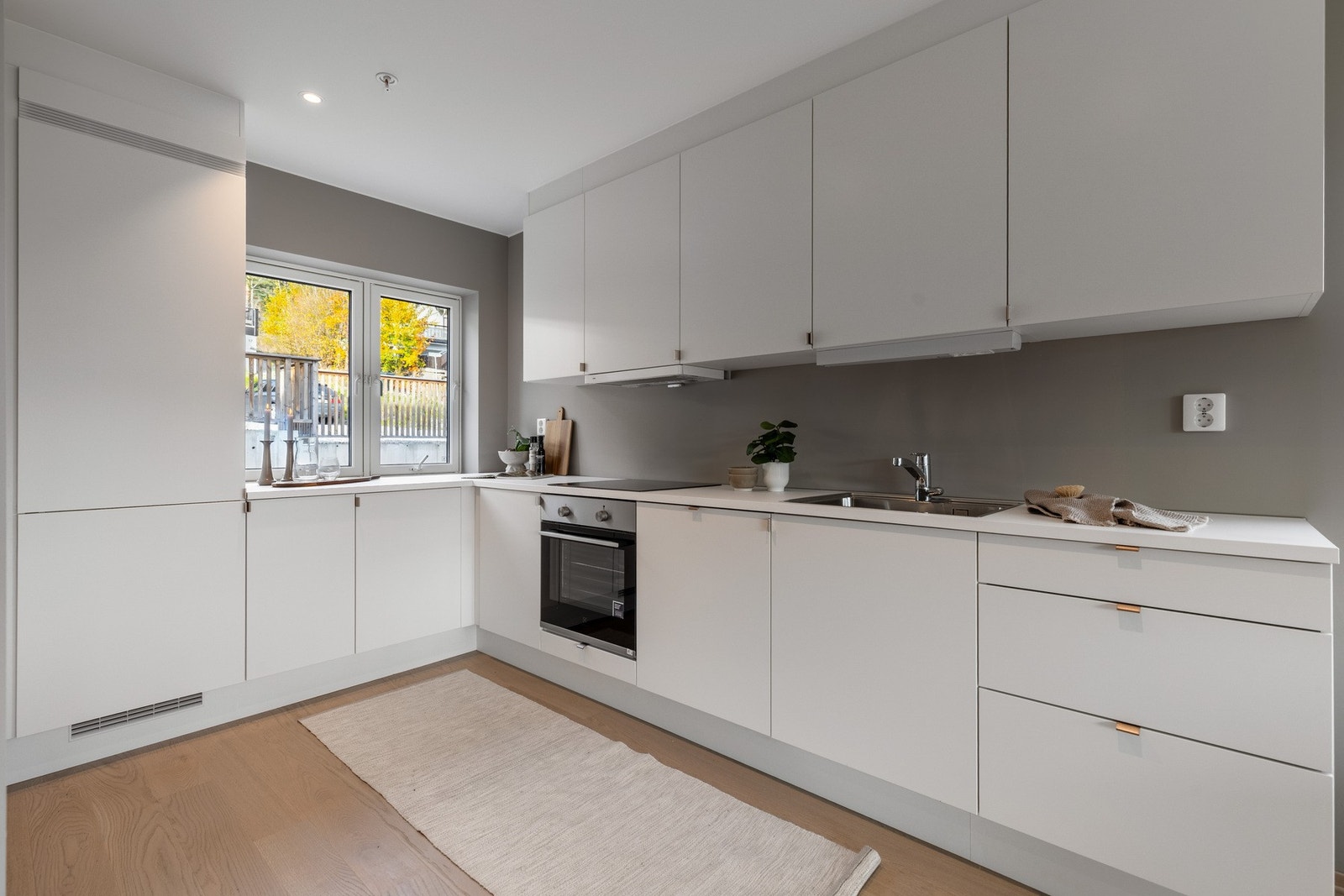 Lyst og moderne kjøkken med integrerte hvitevarer og god benkeplass. Galleribilde