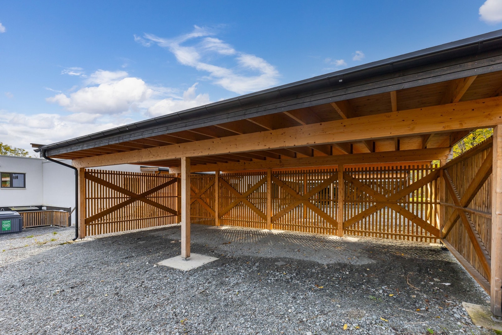 Carport med plass til flere biler, gruslagt gulv og solid treverk i konstruksjonen. Galleribilde