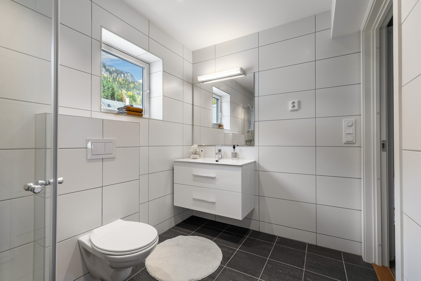 Praktisk innredning med servant, vegghengt toalett og dusjhjørne. Galleribilde