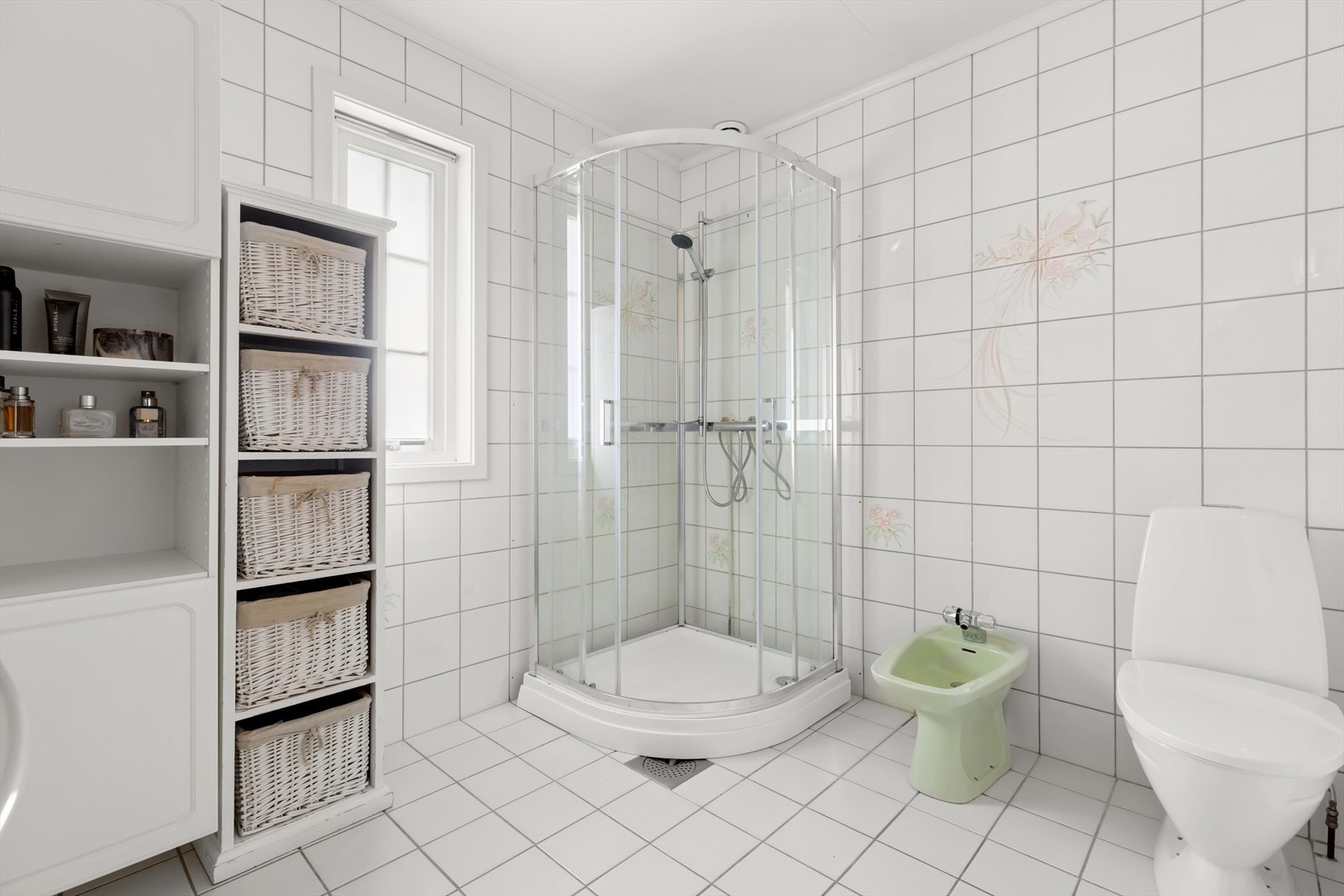 Baderommet i 1. etasje har adkomst fra soverommet og er utstyrt med gulvstående klosett, et nyere dusjkabinett fra 2024, et bidé og en enkel servant. Galleribilde