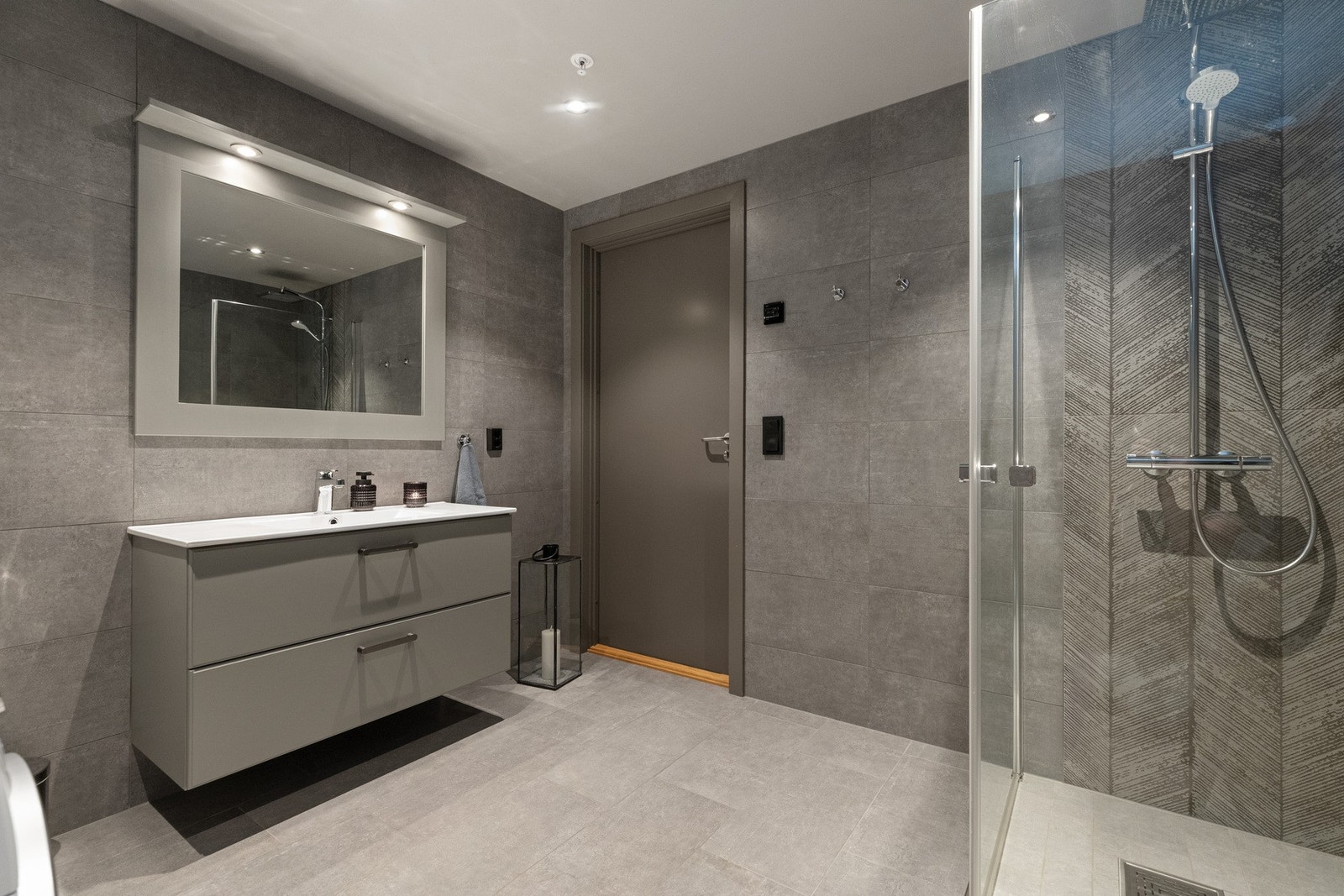 Stort baderom med bred innredning som har to skuffer. Speil med ramme og lys. Galleribilde