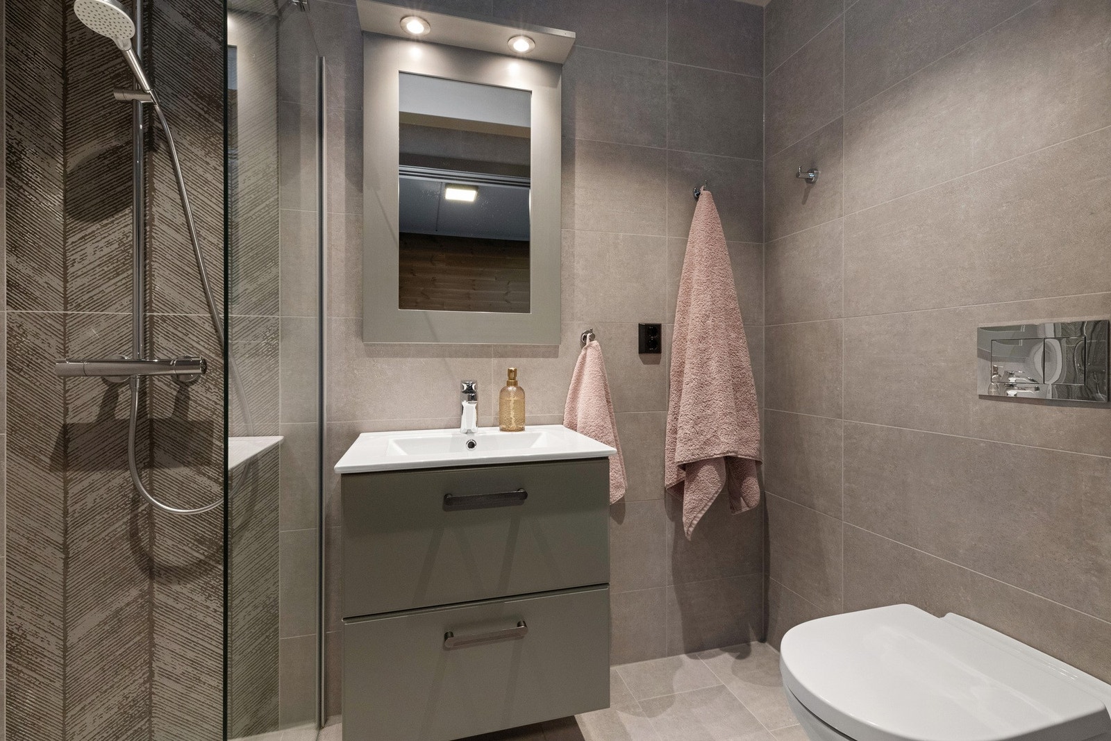 Delikat bad tilhørende hovedsoverom. Fliser på gulv og vegg. Regnfallsdusj, samt hånddusj. Galleribilde