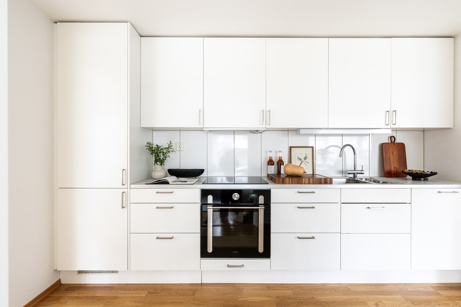 Stilrent kjøkken fra Marbodal hvor kjøkkeninnredningen består av hvite, glatte fronter og benkeplate av laminat med nedfelt vask- og skyllekum. Galleribilde