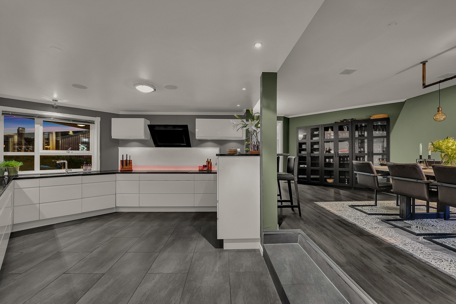 Kjøkkenet ligger åpent mot en flott spisestue med utgang til en nordøstvendt balkong. Det er to trappetrinn mellom spisestuen og kjøkkenet, der kjøkkensonen har fliser og spisestuen har mørkt, enstavs laminatgulv Galleribilde