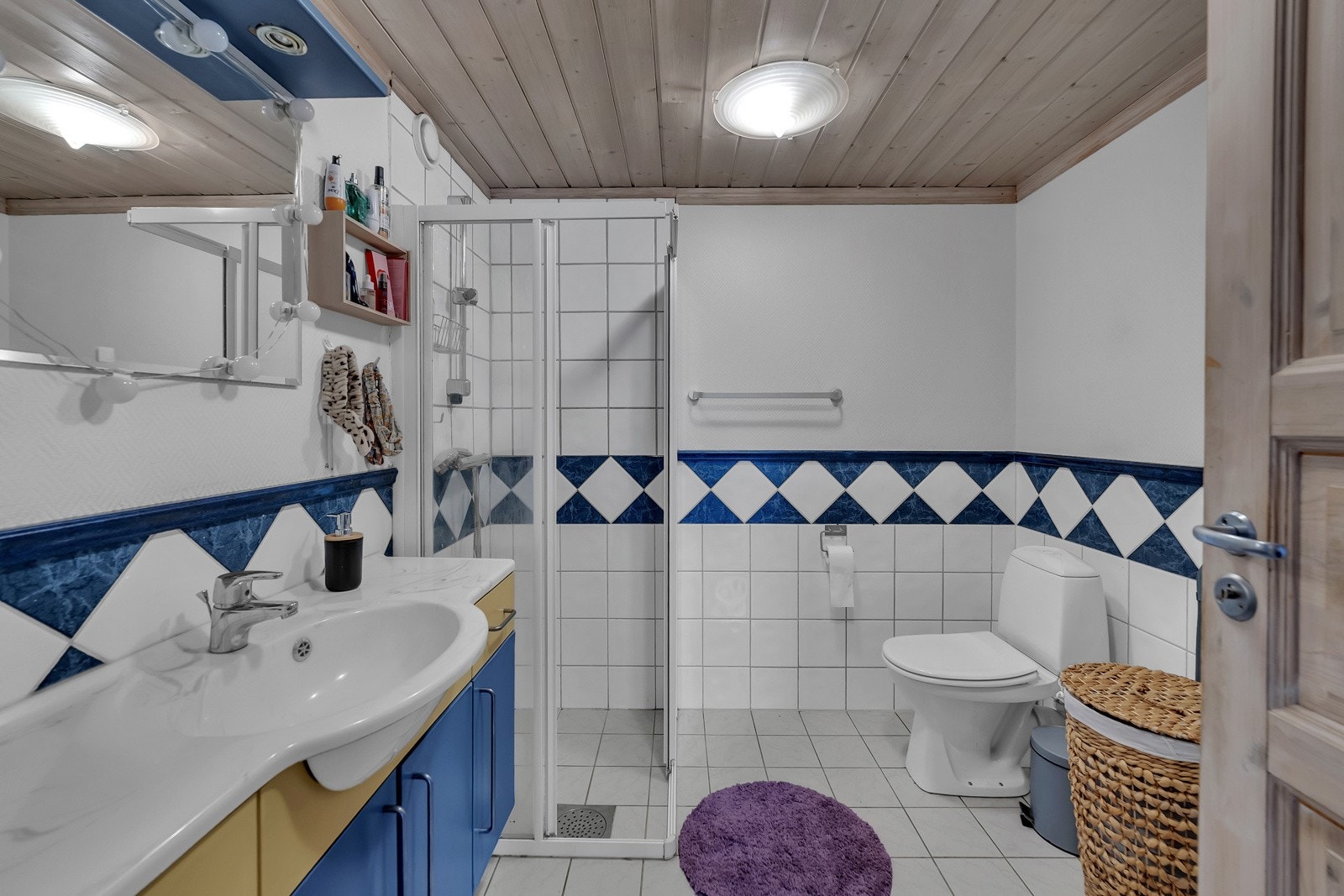Badet i utleiedelen har fliser på gulvet og til brystningshøyde på veggene, lysmalte vegger ellers og panelhimling med plafond. Badet har også opplegg for vaskemaskin. Galleribilde
