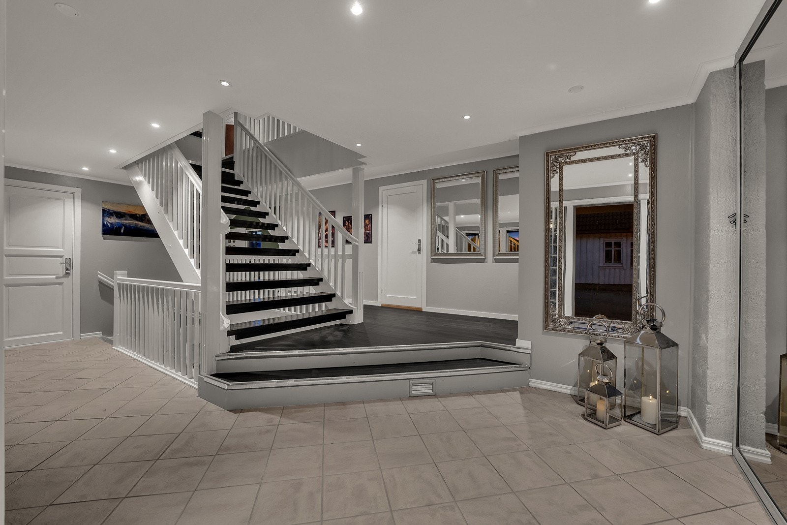 Hallen i første etasje er representativ med gråmalte veggflater, glatt himling med downlights, flislagt gulv og dagslys fra to vinduer mot gårdsplassen. Rommet har vannbåren gulvvarme, noe som også gjelder for øvrige rom i boligen. Galleribilde