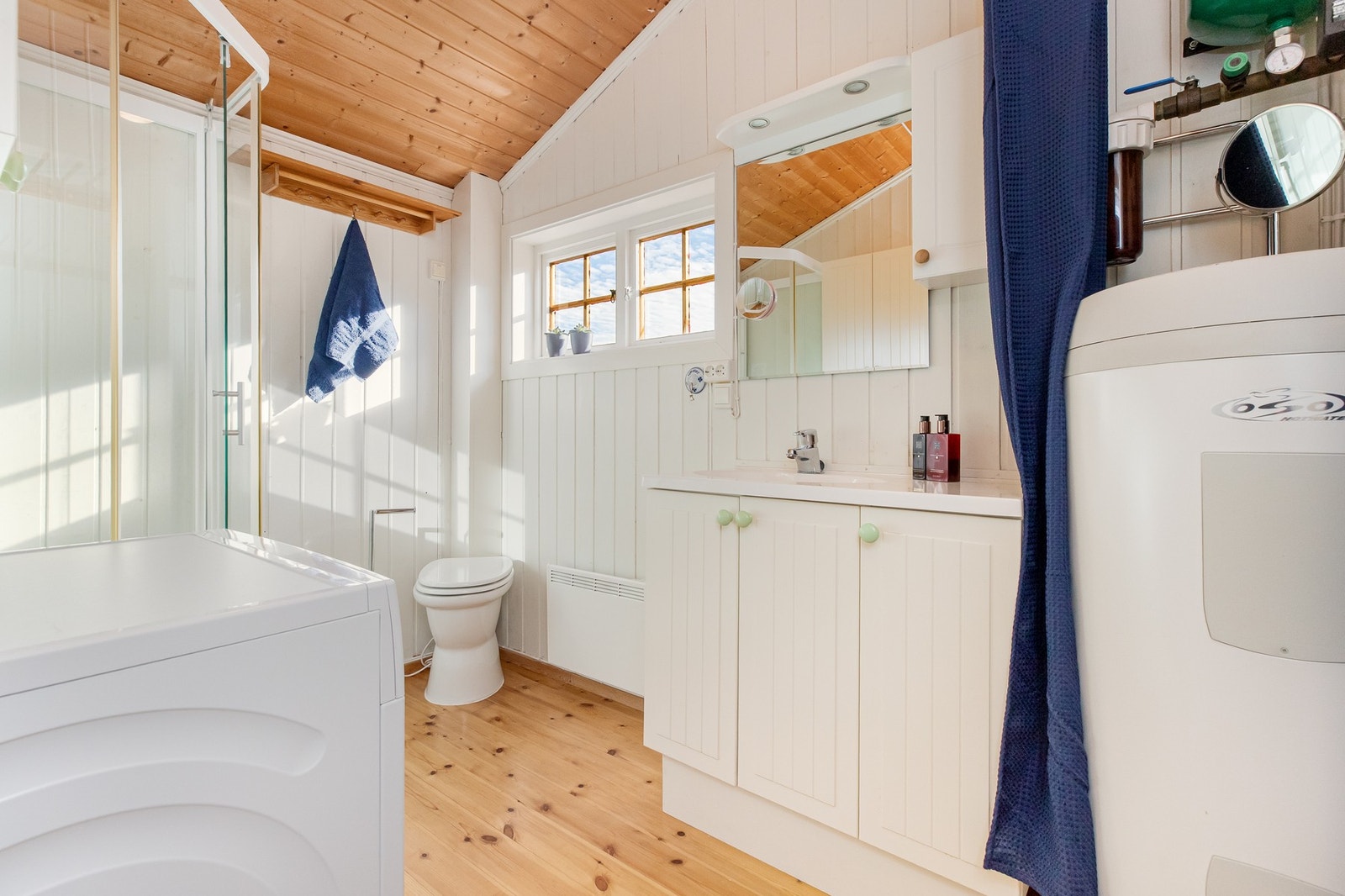 Badet har gulv belagt med lakkert tregulv, vegger er kledd med malt trepanel og himling er kledd med trepanel Galleribilde