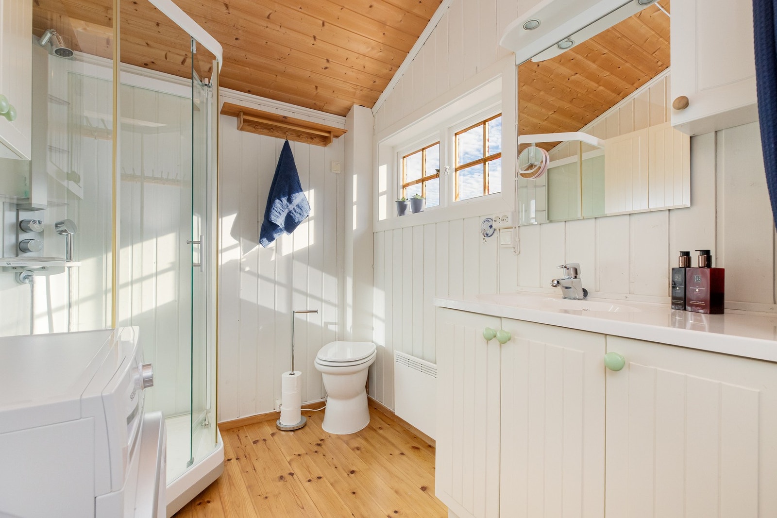 På badet finner man montert dusjkabinett, servant, opplegg til vaskemaskin og snurredo med vifte for lufting Galleribilde