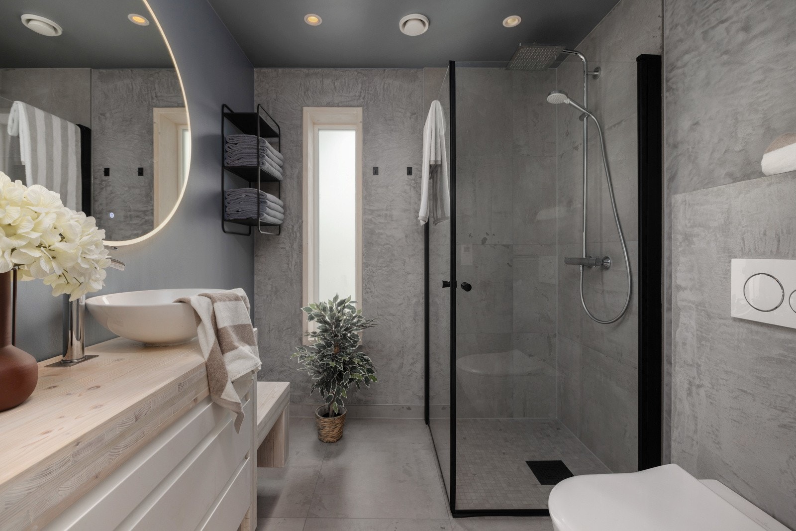 Bad hoveddel: Badet har moderne uttrykk med fliser på gulv deler av vegg, og malte plater i tidsriktige farger. Det er vannbåren gulvvarme, dusjhjørne med innfellbare dører, veggmontert toalett, servant med underskap og speil med belysning. Galleribilde