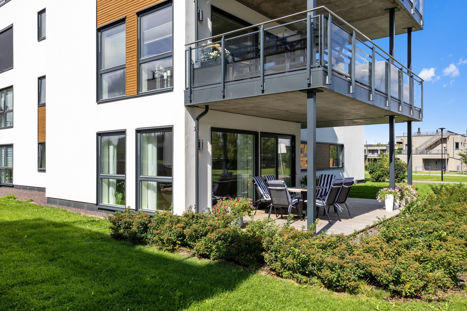 Leiligheten har sin egen terrasse, delvis overbygget og innrammet av en frodig blomsterhekk. Galleribilde