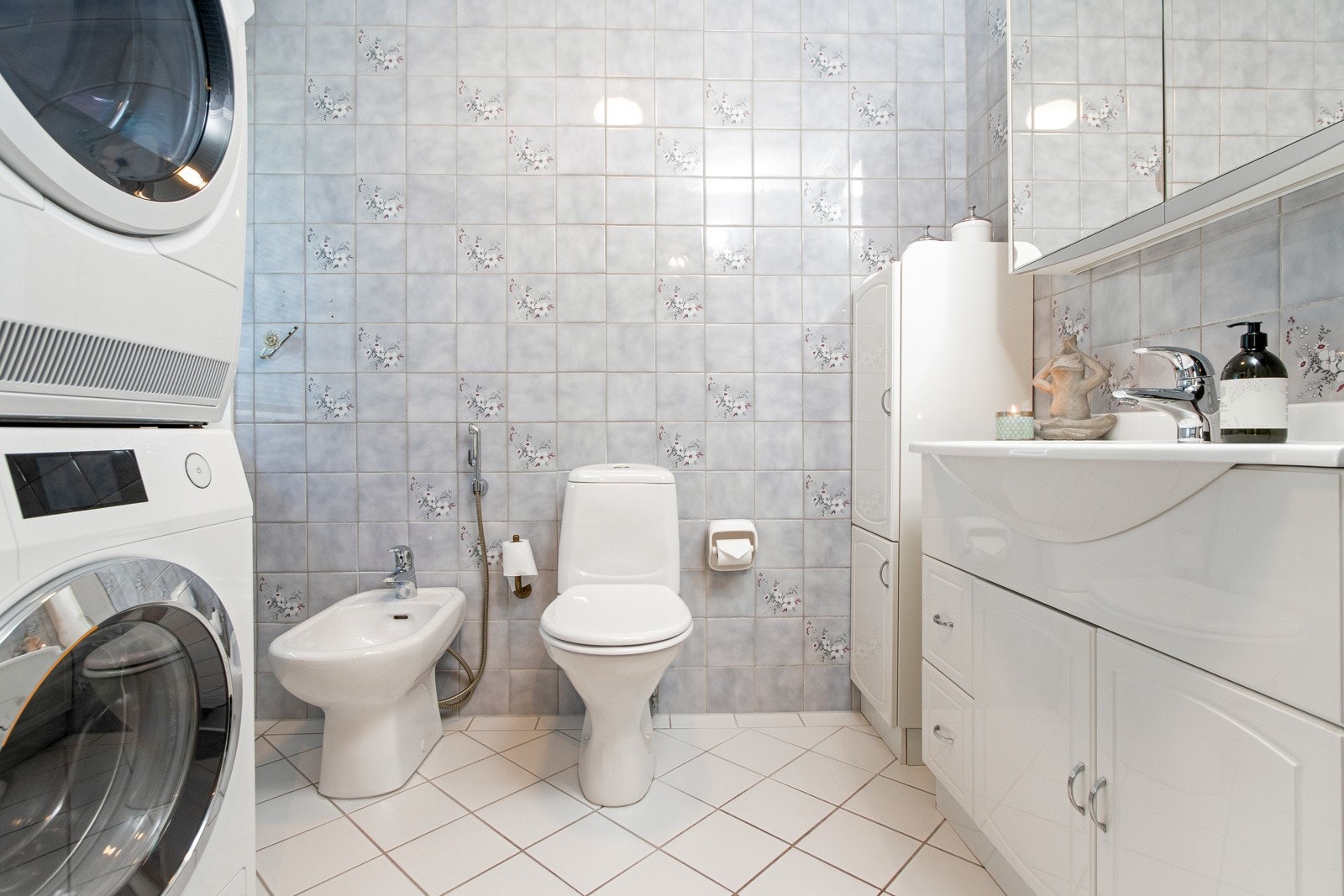 Det andre badet i første etasje er kombinert bad/vaskerom og har lyse fliser på gulvet, fargede fliser på veggene, gulvvarme, bidé, gulvmontert toalett, mulighet for dusj og opplegg for vaskemaskin/tørketrommel. Galleribilde
