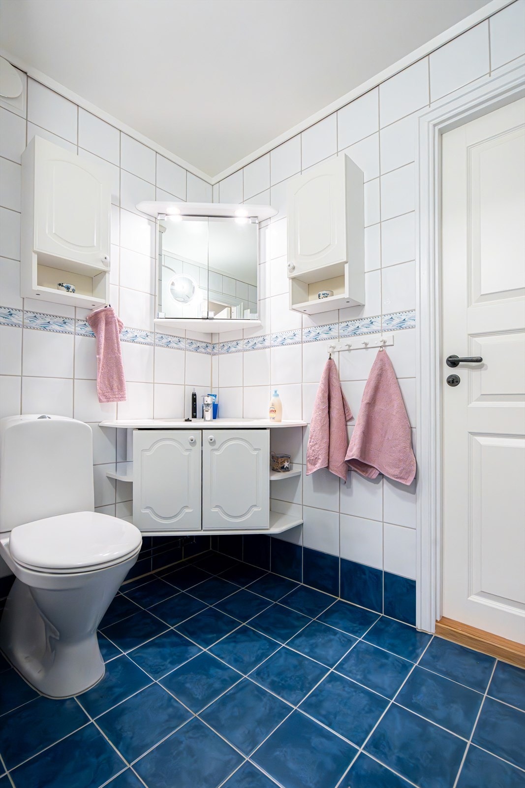 Fliser på gulv og vegger. Baderomsinnredning med profilerte, folierte fronter og nedfelt servant. Speilskap med lys, samt tilhørende veggskap. Gulvmontert toalett. Galleribilde