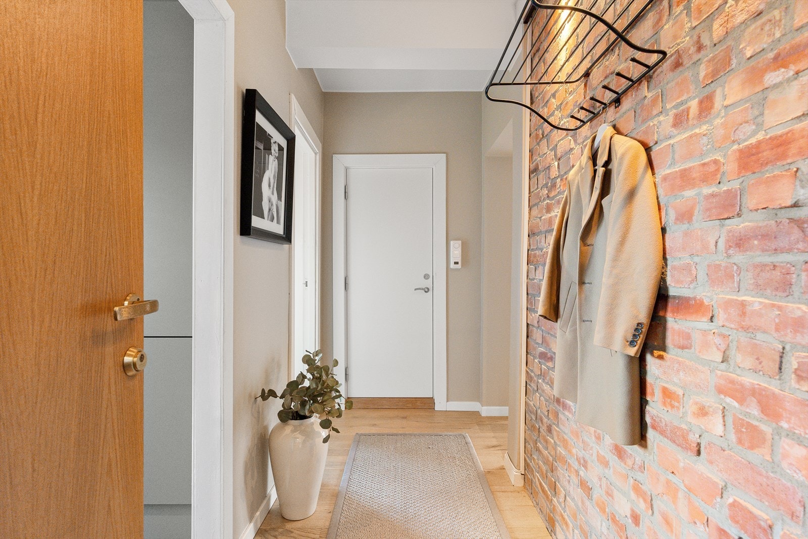 Velkommen inn! Leiligheten har en innbydende entré som skaper et umiddelbart godt førsteinntrykk. Her kan du enkelt henge i fra deg yttertøy. Galleribilde