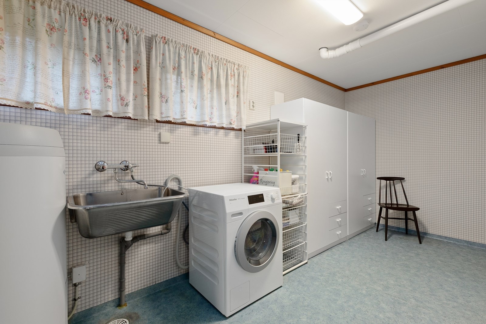 Stort vaskerom med utslagsvask, opplegg for vaskemaskin og varmtvannsbereder. Galleribilde