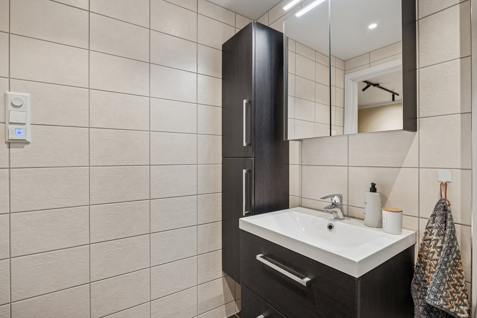 Badet er utstyrt med opplegg til vaskemaskin, innredning med nedfelt servant, veggmontert toalett og dusjvegger/hjørne. Galleribilde