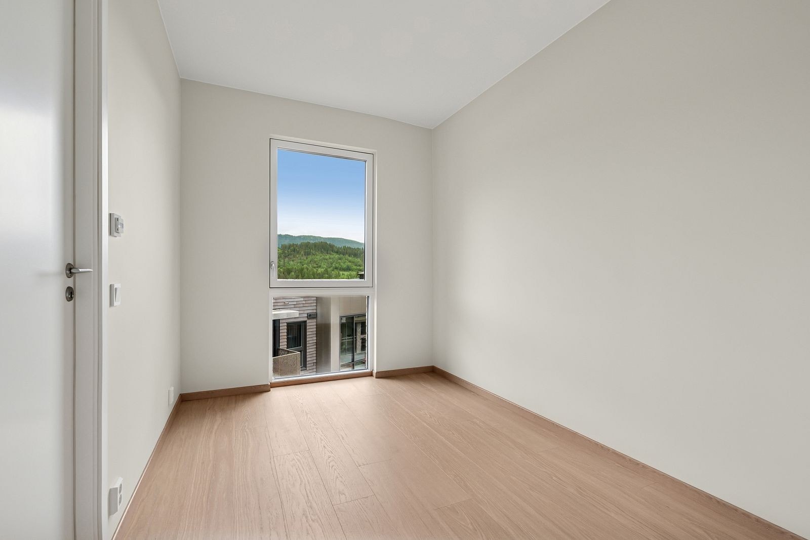 Fra det andre soverommet kan man nyte en fantastisk utsikt gjennom et imponerende takhøyt vindu som vender mot sør. Rommet bader i naturlig lys, og gir en følelse av åpenhet og frihet. Galleribilde