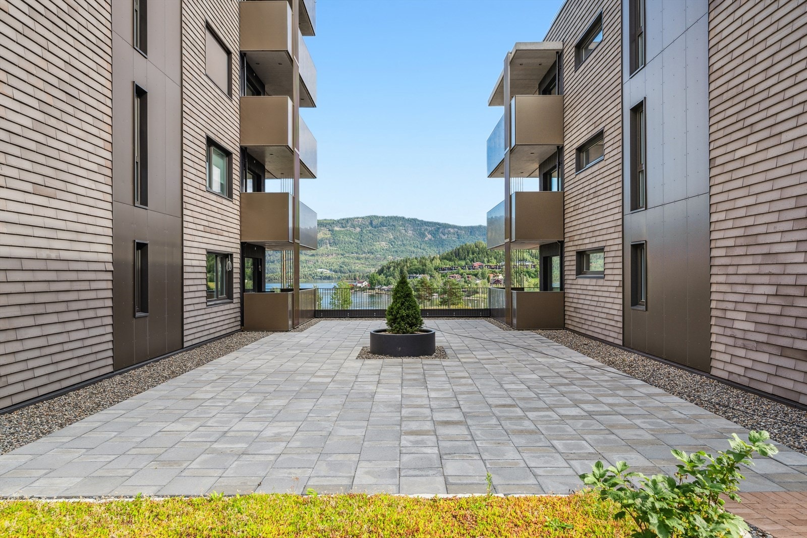 Mellom blokkene finner du et romslig og gjennomtenkt opparbeidet tomteareal. Her er det lagt vekt på grønne kvaliteter med sedumdekke, samt solide og estetiske løsninger med belegningsstein. Området fremstår som både funksjonelt og innbydende. Galleribilde