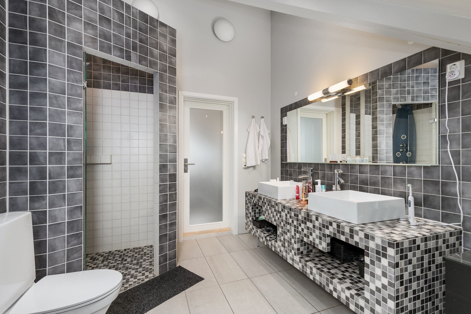 Pent hovedbad i 2. etasje, med fliser på gulv og delvis fliser på vegg. Åpen baderomsinnredning bestående av benkeskap med fliser. Speil og belysning over servant. Badet har fått TG2 membran, tettesjikt og sluk, samt TG3 på overflater. Galleribilde