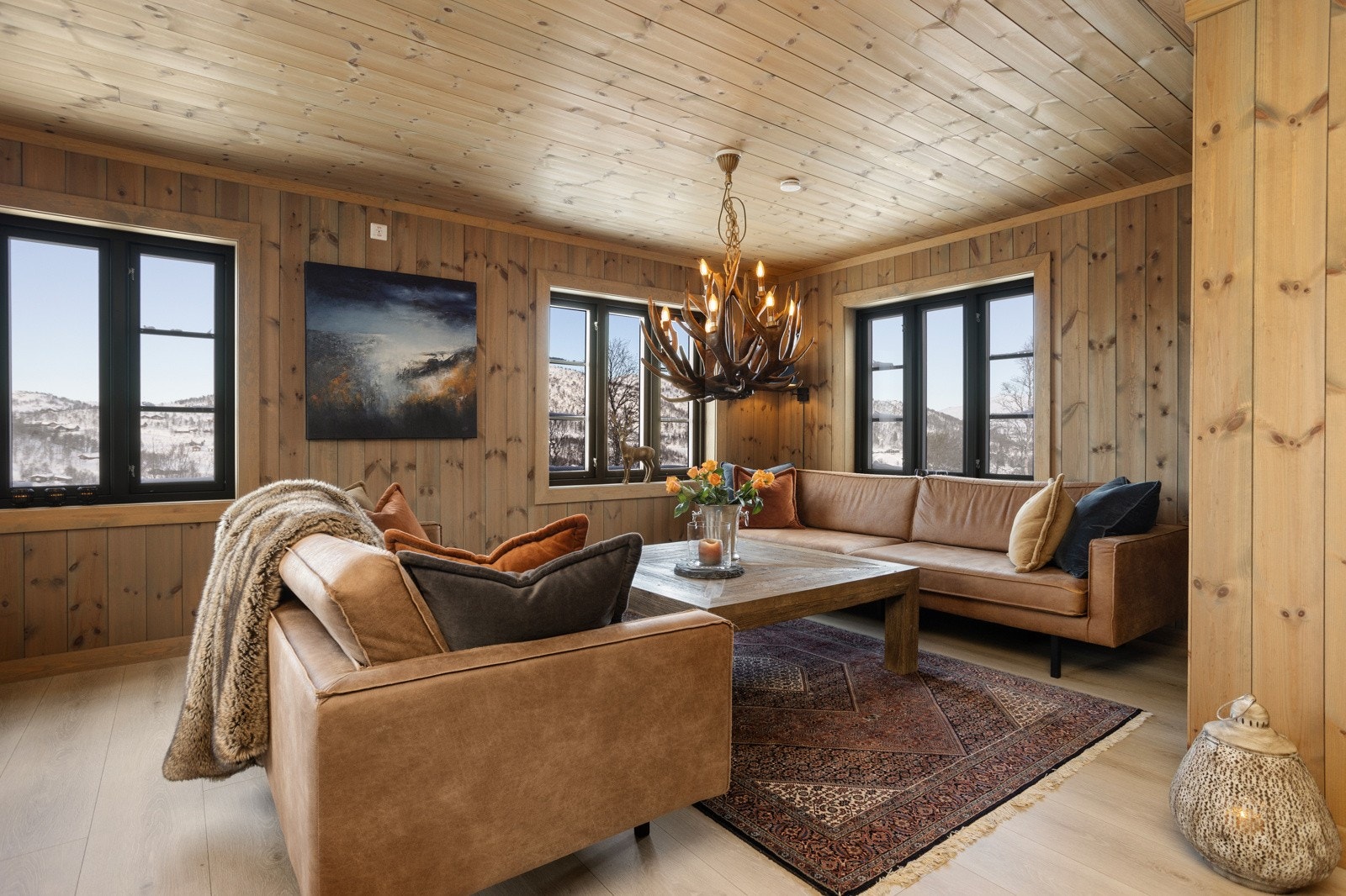 Stuen har store vinduer som gir rikelig med dagslys, samtidig som man bringer naturen rett inn i sofakroken Galleribilde