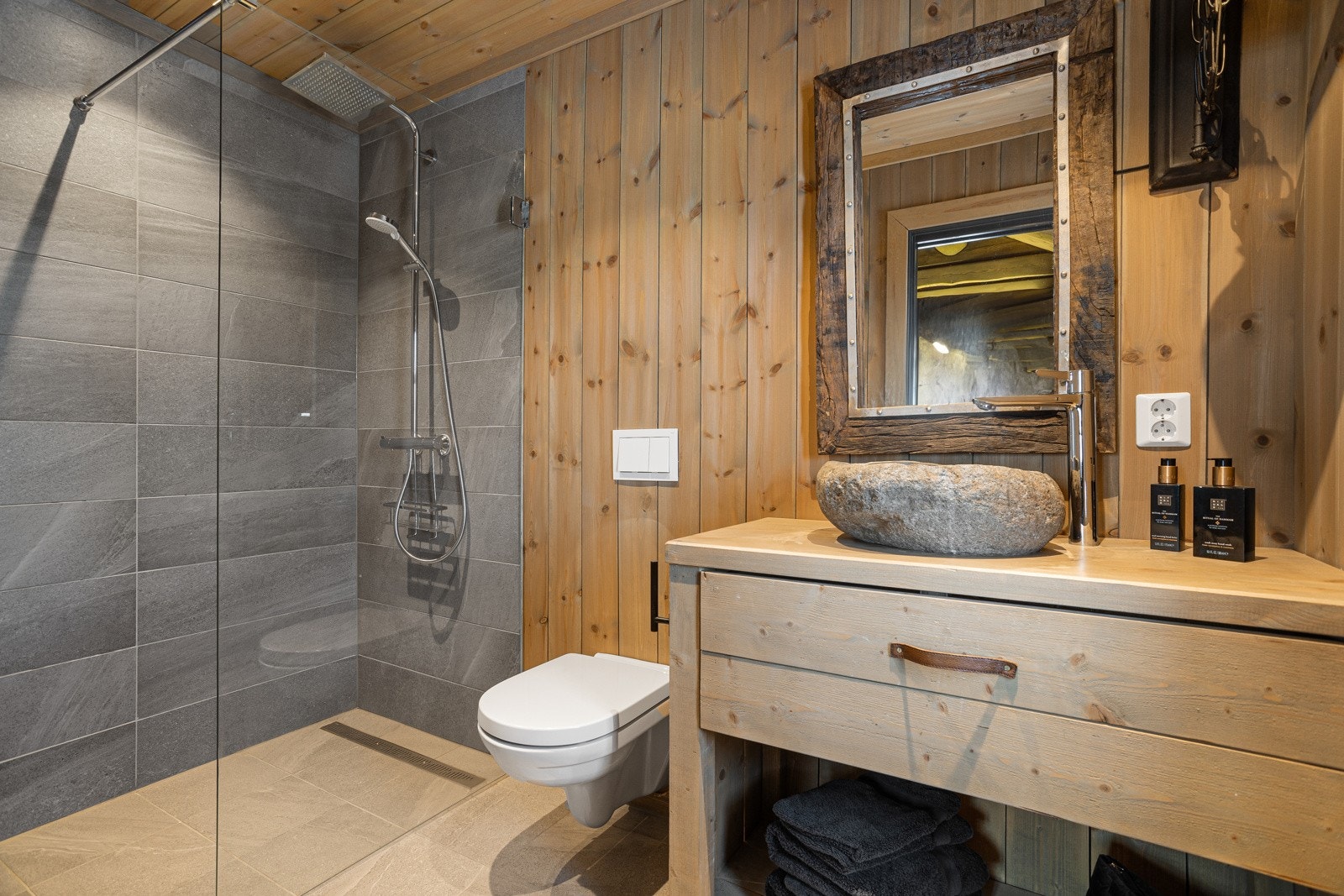 Badet har spesialbygget baderomsmøbel, toppmontert servant og speil, walk-in dusj med waterfall armatur og vegghengt toalett Galleribilde