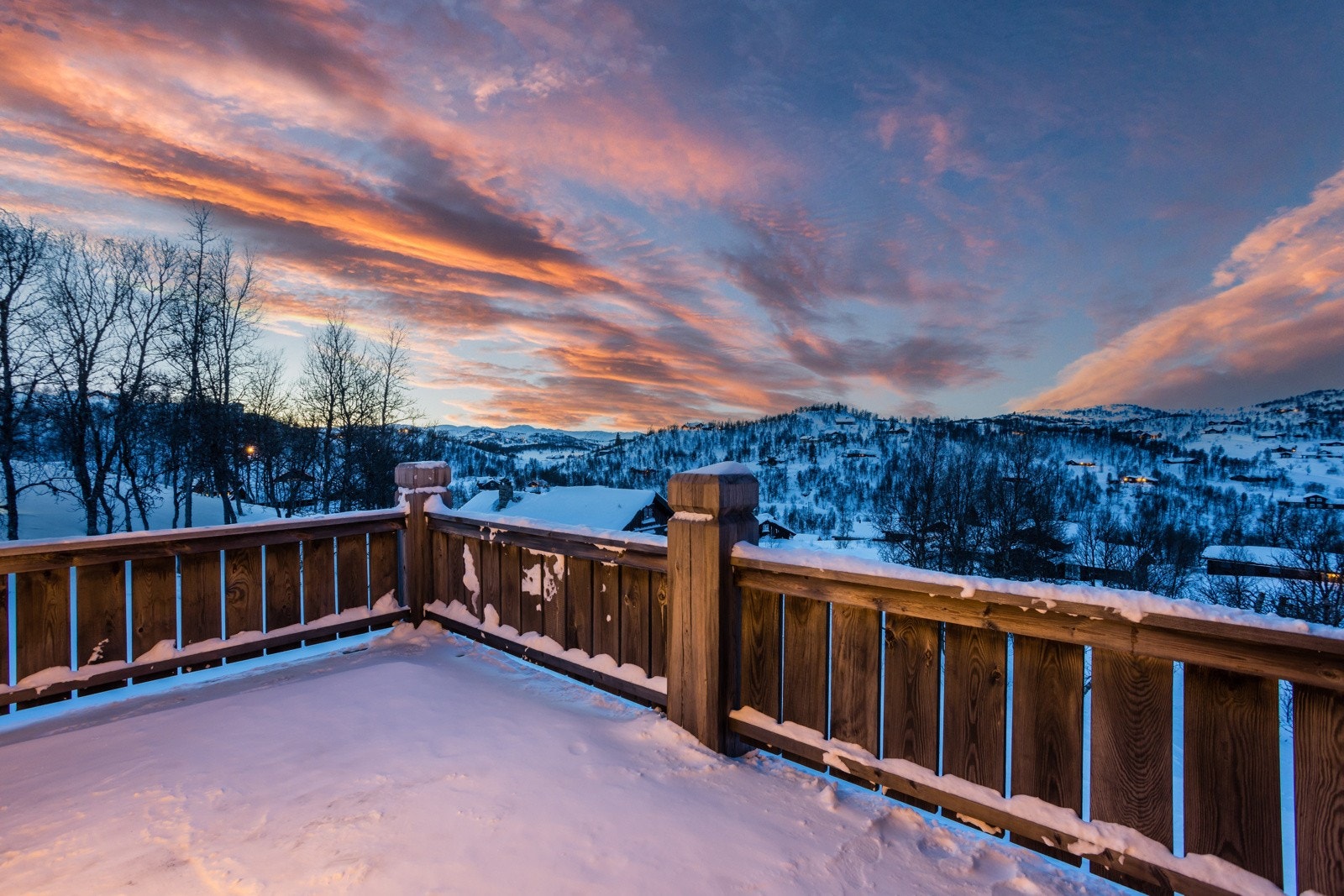 Fra kjøkken er det utgang til solrik terrasse som strekker seg rundt flere sider av hytta Galleribilde