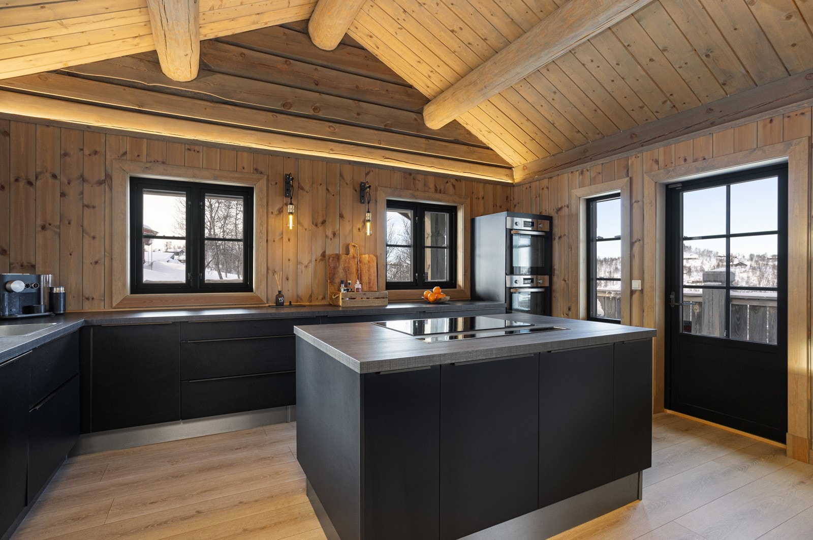 Kjøkkenet har integrerte hvitevarer som induksjon platetopp, skjult ventilator, to stekeovner, oppvaskmaskin og kjøleskap med frysedel Galleribilde