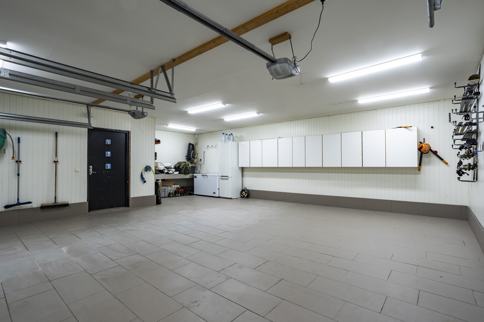 Den integrerte dobbelgarasjen er flislagt og har vannbåren gulvvarme. Her er det god plass til to biler, samt praktisk lagringsmulighet. Galleribilde