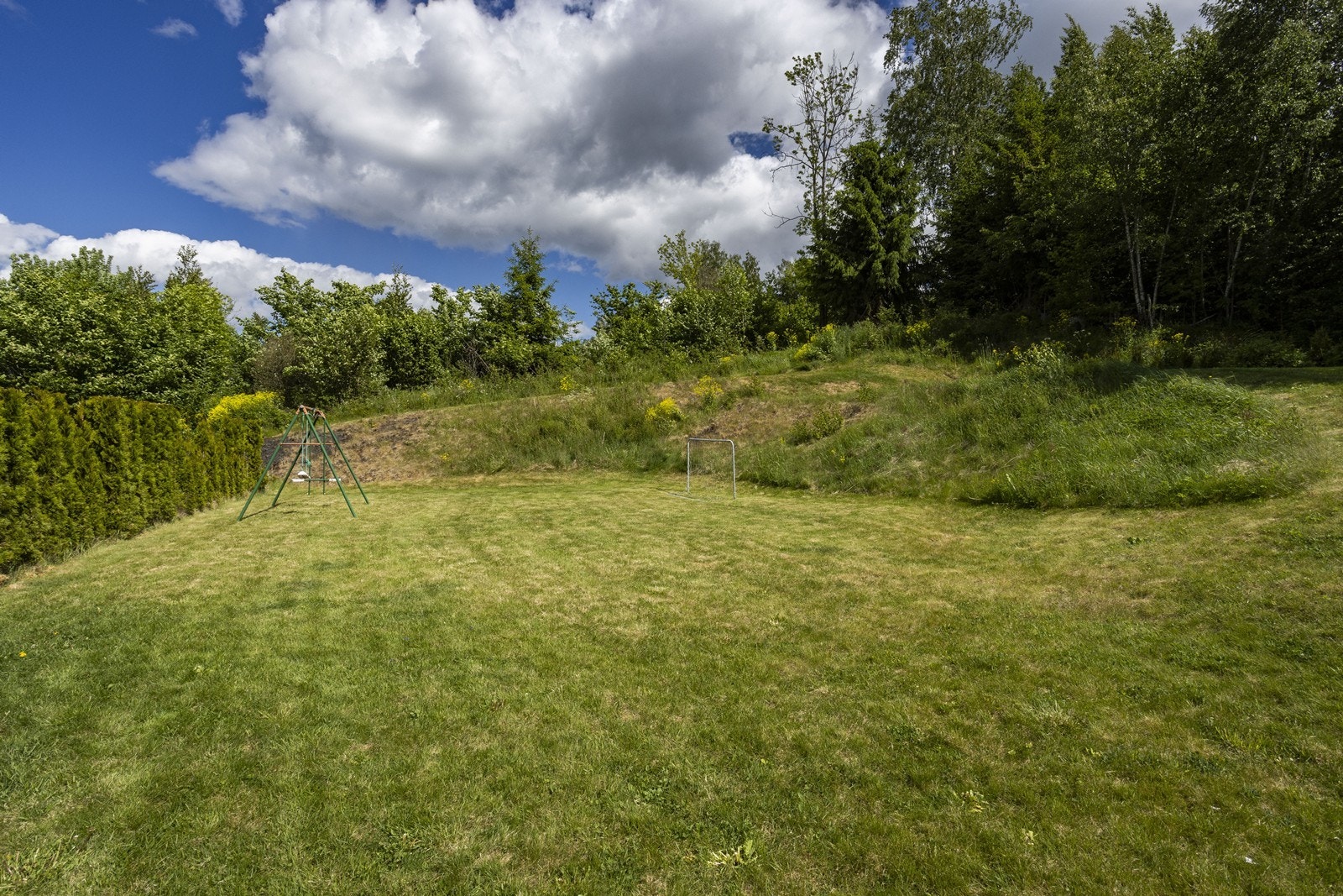 På oversiden av boligen ligger et solrikt og flatt uteområde med plen - perfekt for lek, hygge og uteaktiviteter for hele familien. Galleribilde
