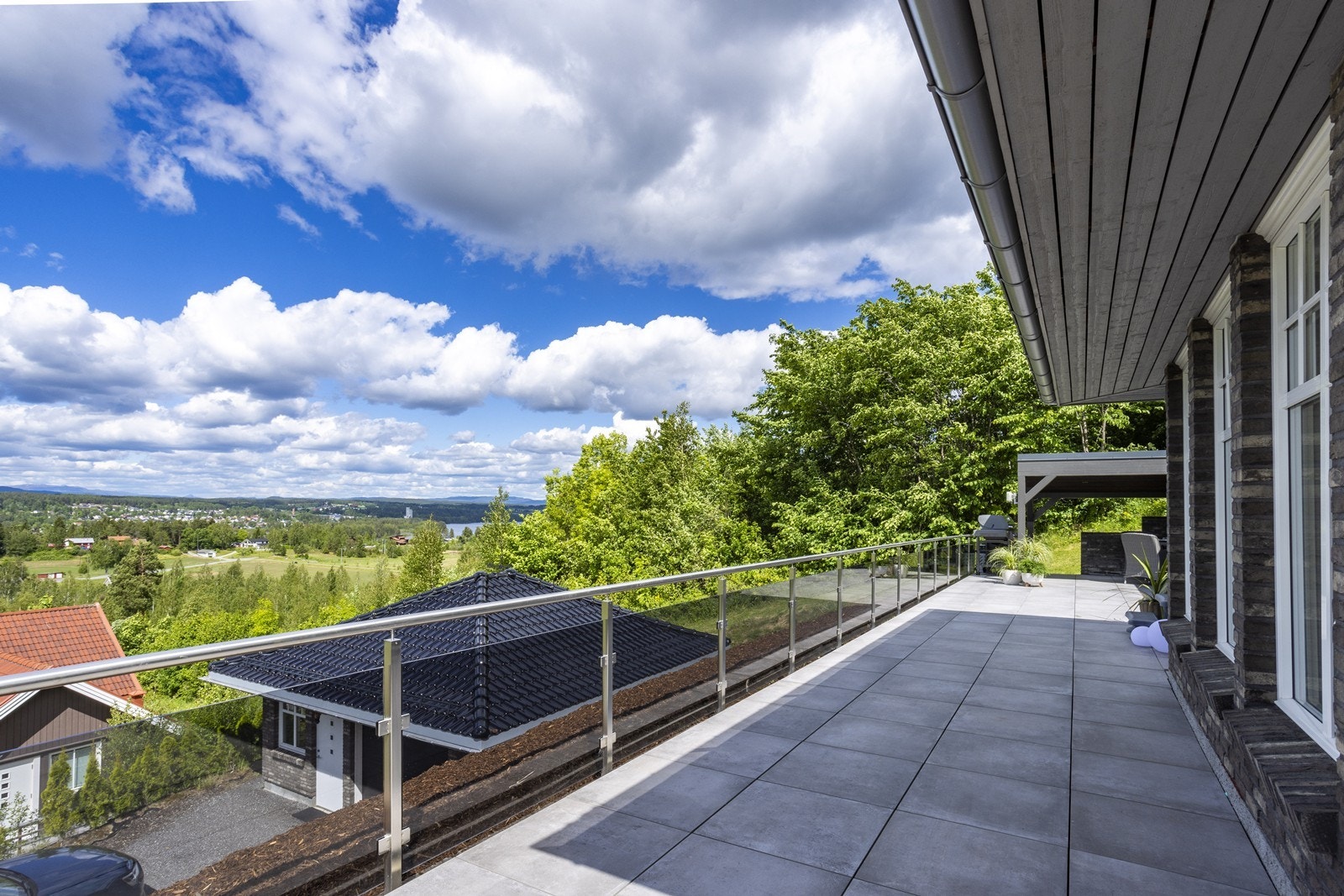 Et moderne glassrekkverk rammer inn uteplassen på stilfullt vis, uten å hindre den fantastiske panoramautsikten. Galleribilde