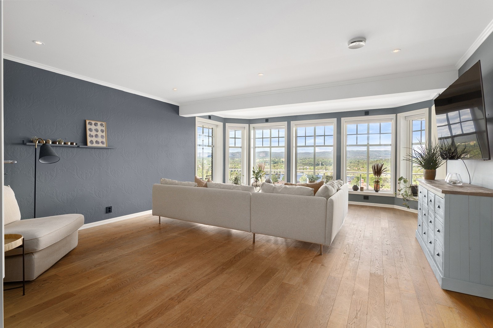 Stuen er elegant malt i en beroligende blåfarge, og stemningen forsterkes av moderne downlights. Galleribilde