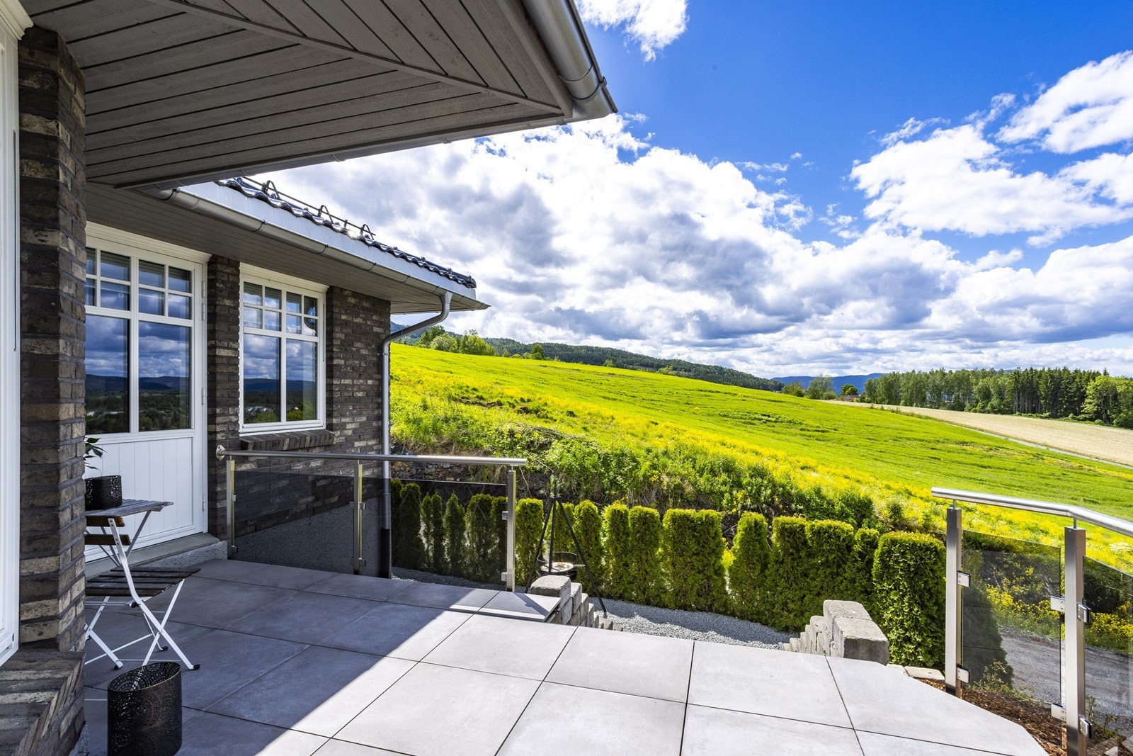 Uteomårdet er pent opparbeidet med steinlagt platting, støttemurer, stentrapper og hekk. Galleribilde