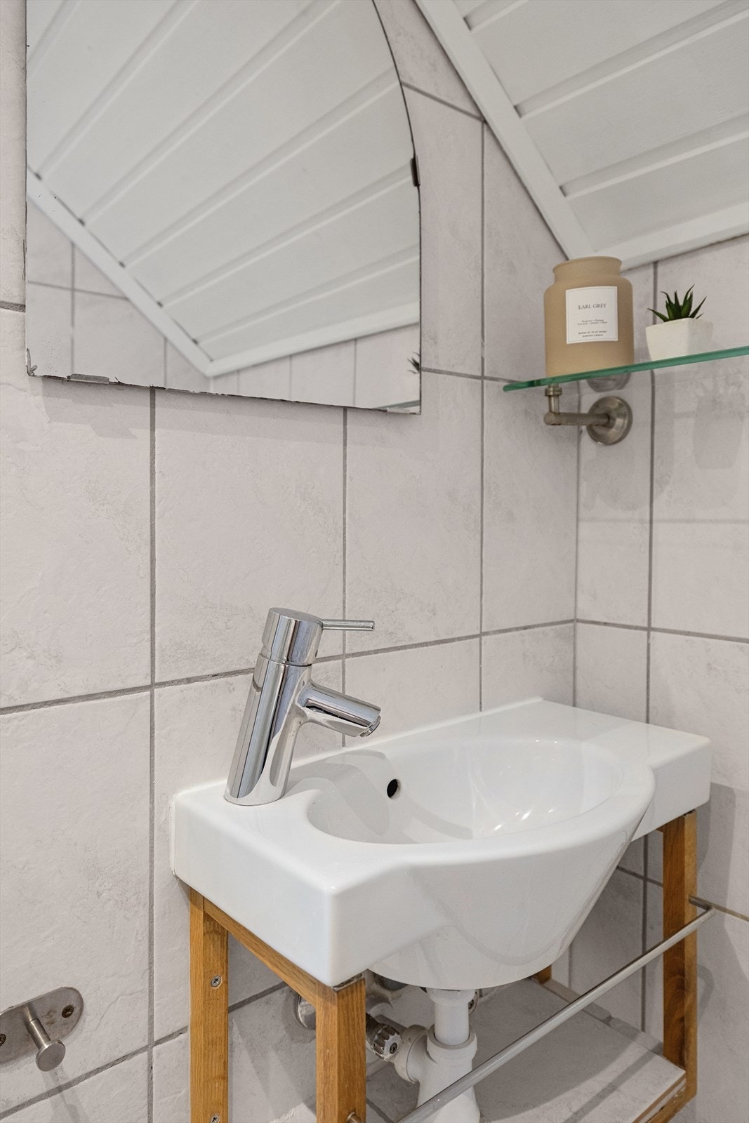 Badet er utstyrt med dusj med glassdør, samt servant og speil Galleribilde