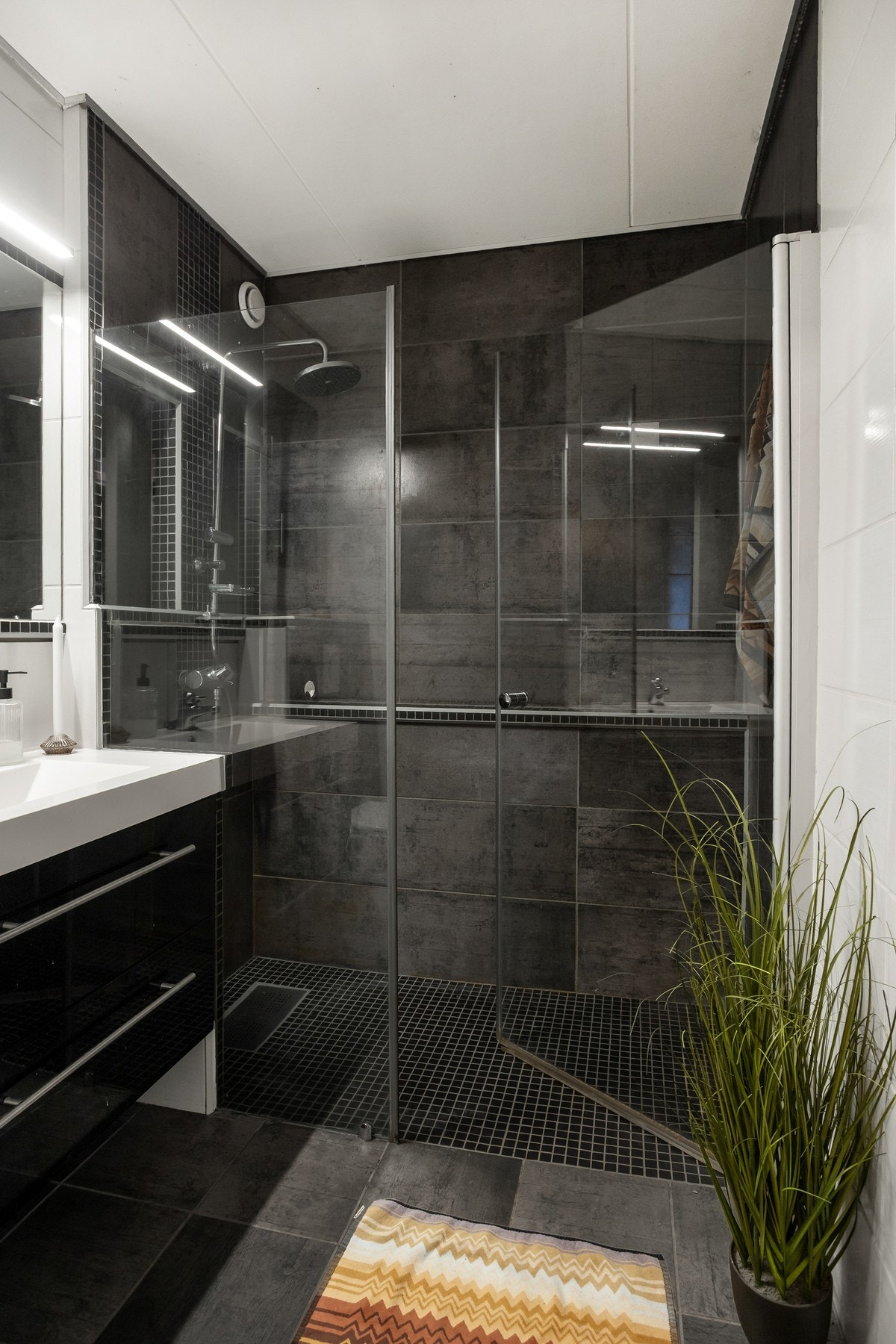 Badet har fliser på gulv med varme, flislagte vegger og malte betongelementer i innvendig tak. Galleribilde