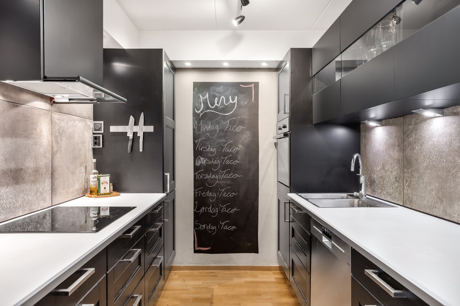 Laminat benkeplate med fliser over benk. Integrert koketopp, stekeovn og kjøl/fryseskap. Opplegg for oppvaskmaskin. Galleribilde