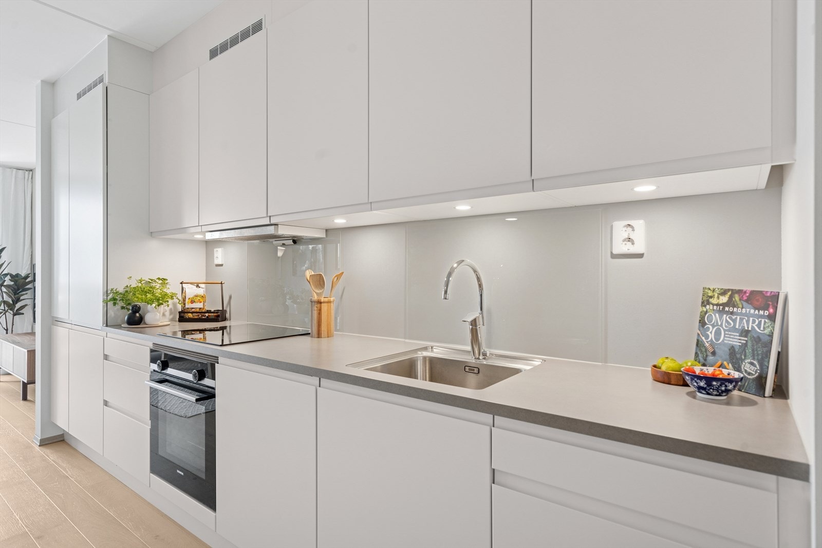 Kjøkkenet er stilrent og lekkert, med hvite, slette fronter og laminat benkeplate. Galleribilde