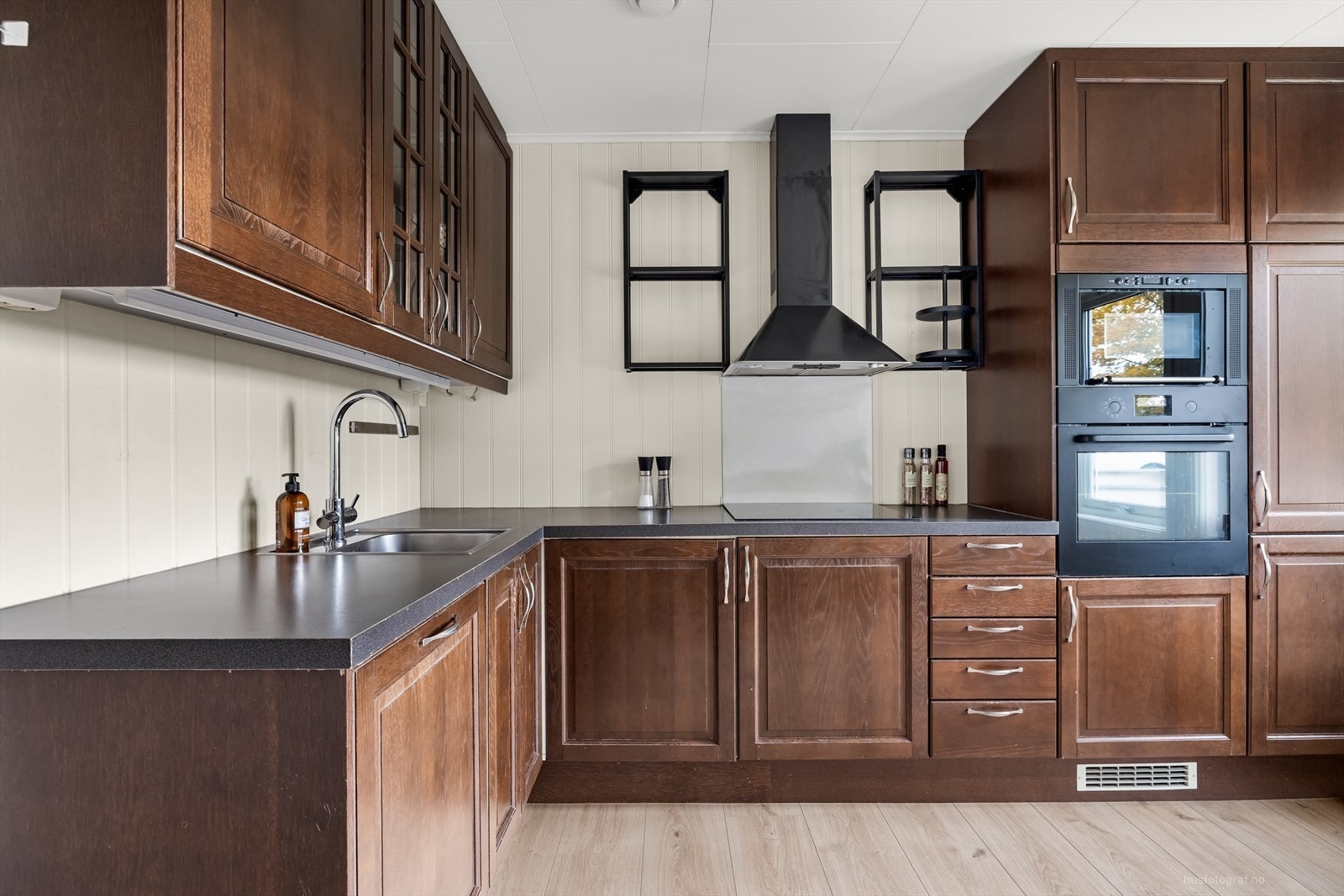 Pent kjøkken med mørke, profilerte fronter og laminat benkeplate. Galleribilde