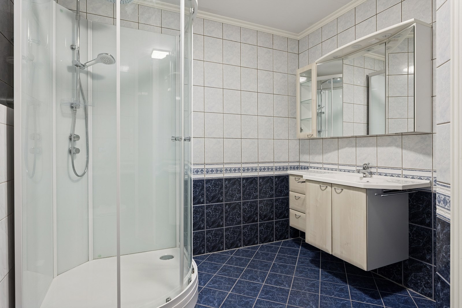 Badet er innredet med seksjon med servant, toalett, dusjkabinett og opplegg for vaskemaskin. Galleribilde