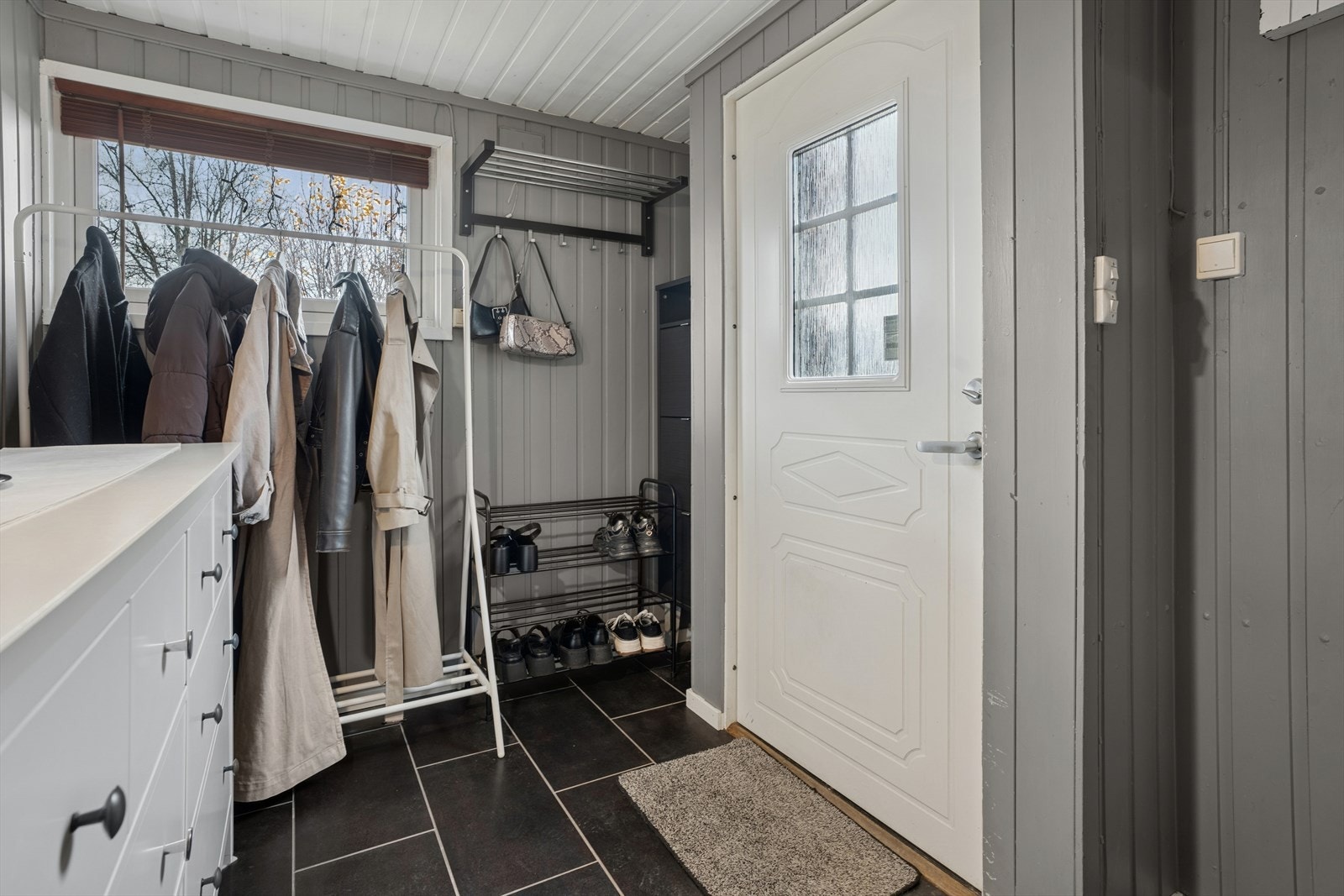 Man ønskes velkommen inn til en romslig entré med fliser på gulvet. Nyere inngangsdør. Galleribilde