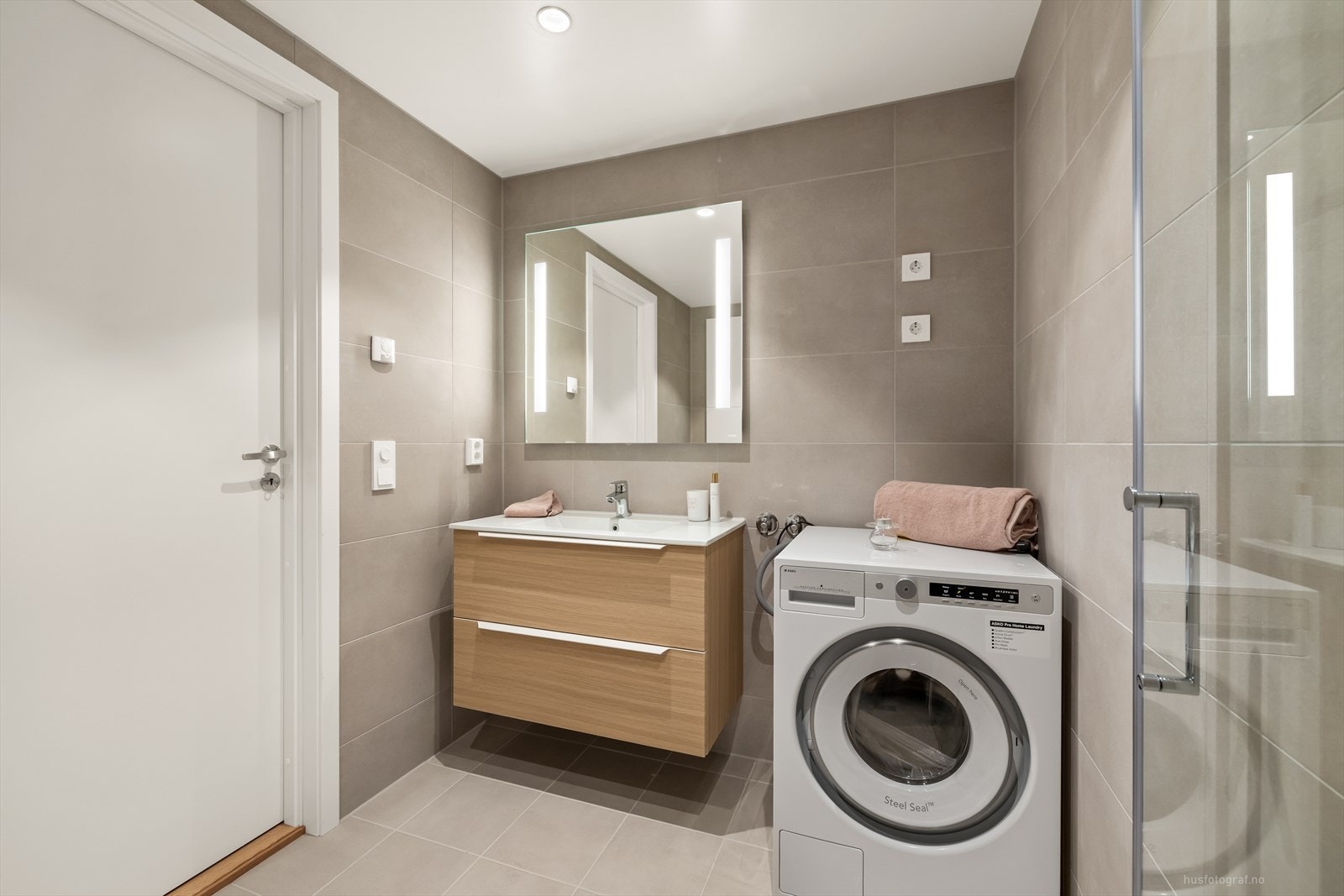 Stilrent og moderne bad med lyse fliser, varmekabler i gulv og en utstrakt bruk av downlights i himling. Galleribilde