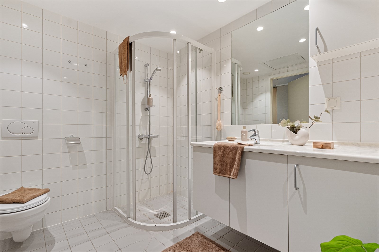 Badet er innredet med vegghengt toalett, dusjhjørne, speil og belysning. Galleribilde