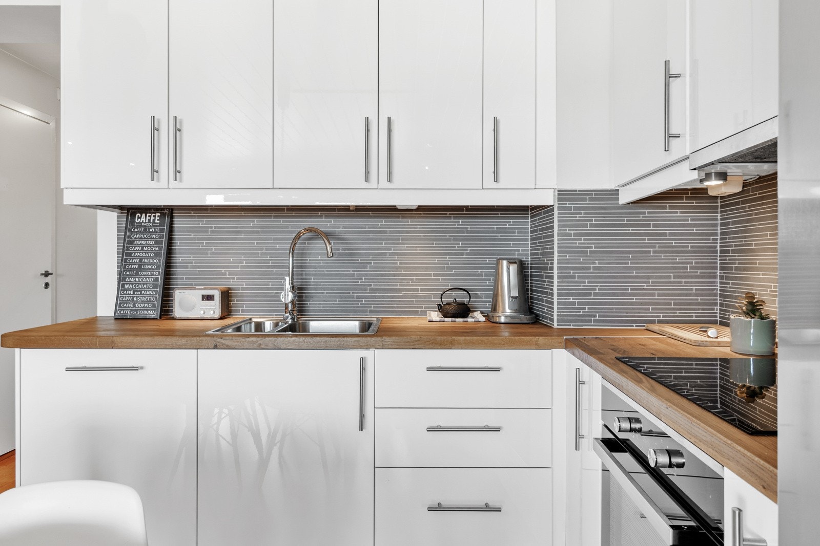 Moderne kjøkken fra IKEA med hvitevarer. Kjøkkenet er effektivt utnyttet med en praktisk planløsning som gir både godt med benkeplass og smarte oppbevaringsløsninger. Galleribilde