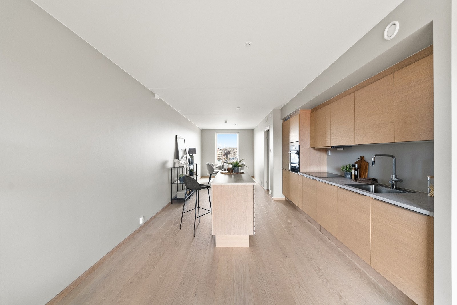 Innredningen består av glatte fronter med foring opp til tak og laminat benkeplate med nedfelt vaskekum. Belysning under overskap. Komfyrvakt er monert over koketopp. Galleribilde