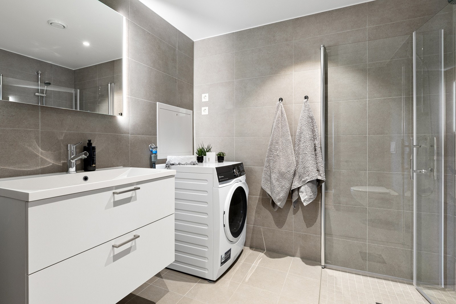 Lyst og pent baderom med dusjhjørne og god oppbevaringsplass. Galleribilde