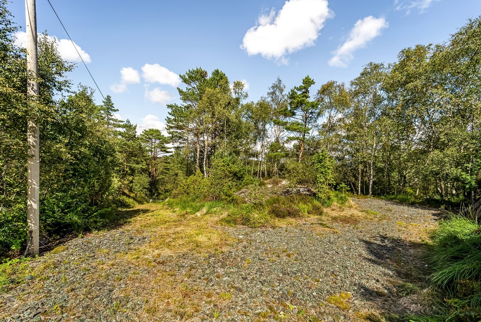 Gruset innkjørsel til eiendommen med plass til parkering. Galleribilde