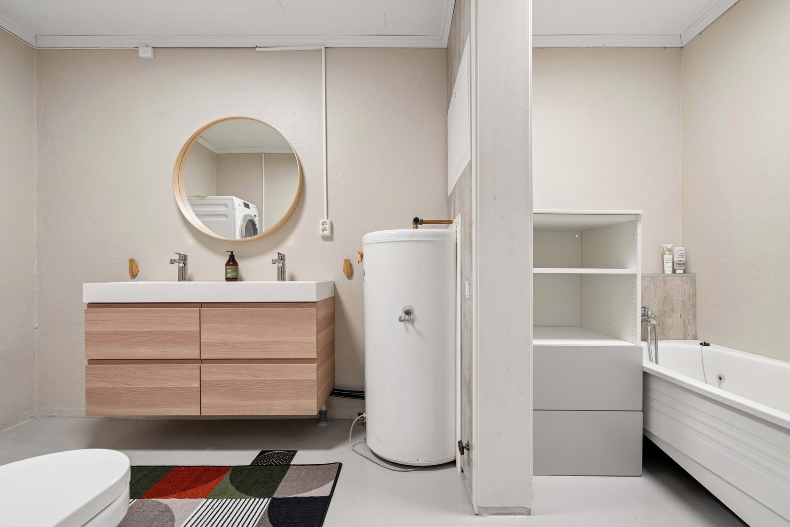 Innredning med to nedfelte servanter, veggmontert toalett, badekar og opplegg for vaskemaskin. Galleribilde