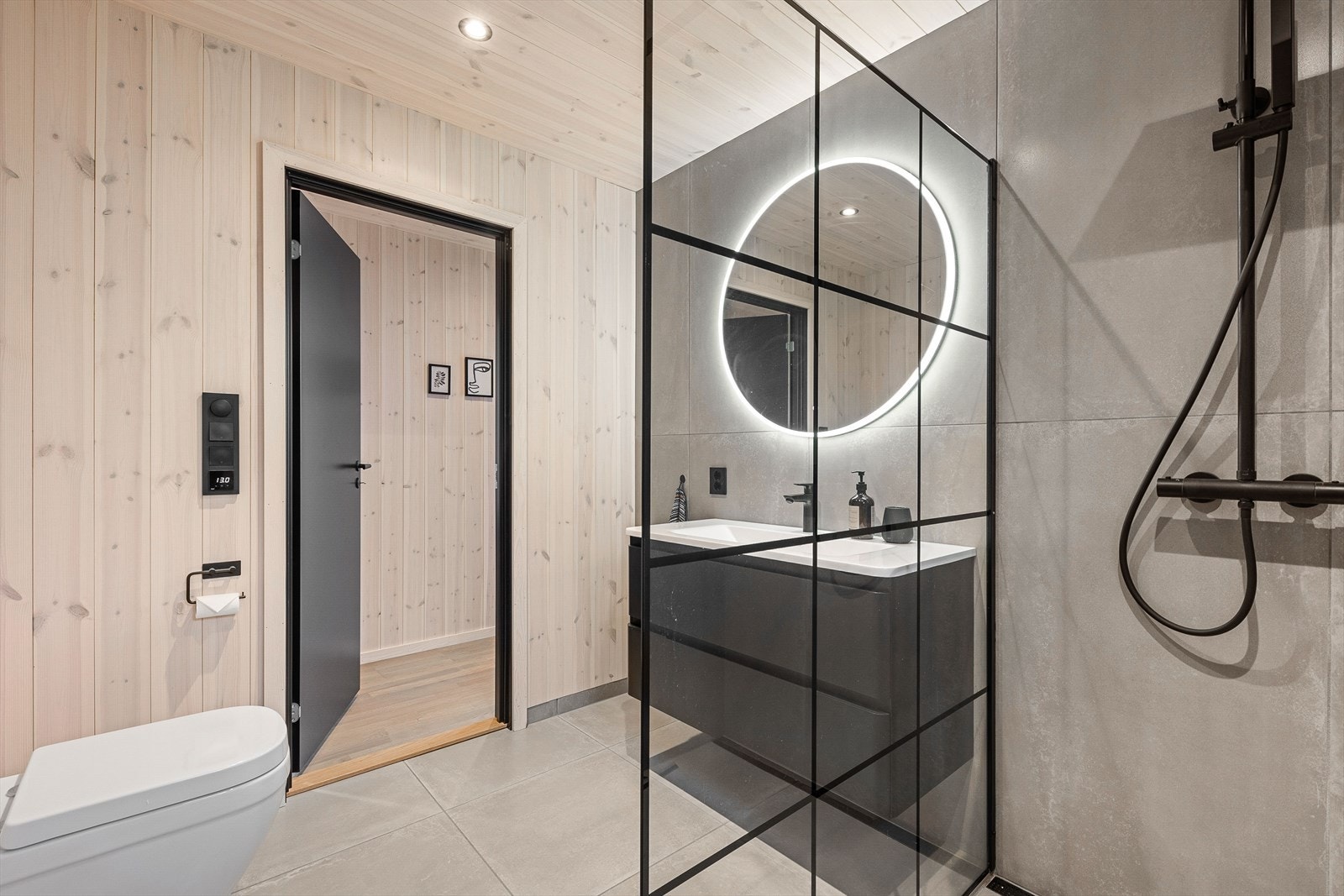 Badet er utstyrt med heldekkende servant over skuffeinnredning, vegghengt toalett og dusjhjørne. Varmekabler i gulv Galleribilde