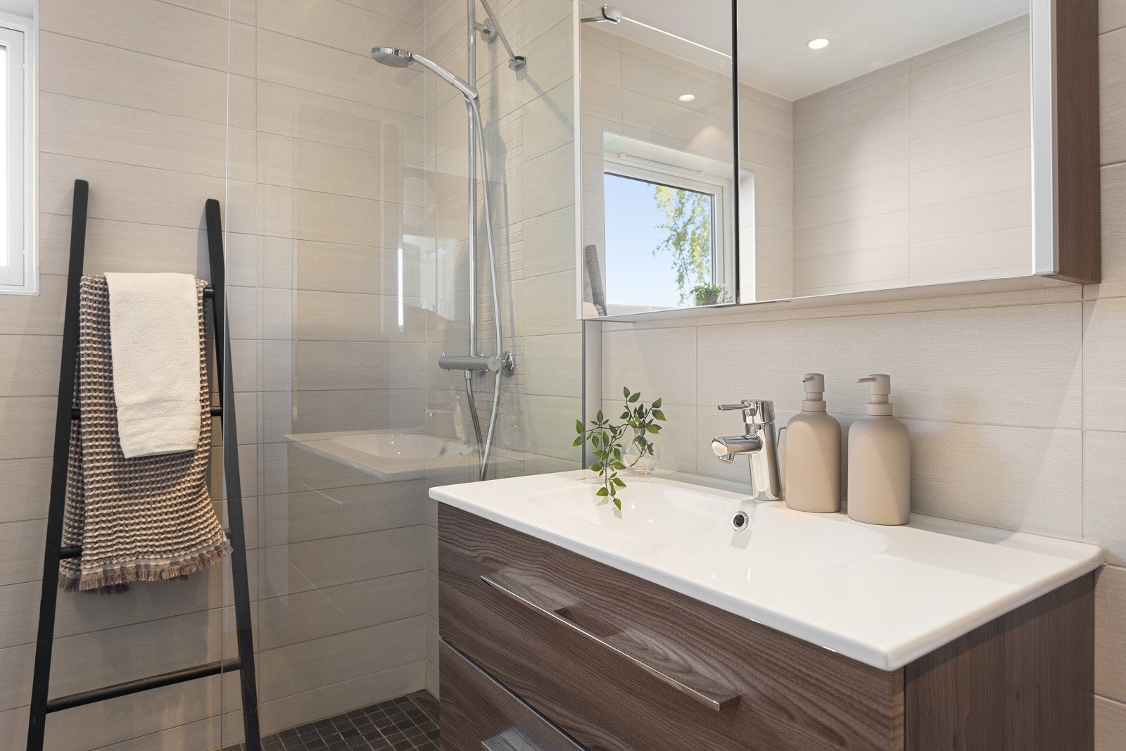 Badet i første etasje ble pusset opp i 2015. Det har flislagte vegger og gulv, malt tak med downlights, innmurt badekar, dusjhjørne og veggmontert toalett Galleribilde