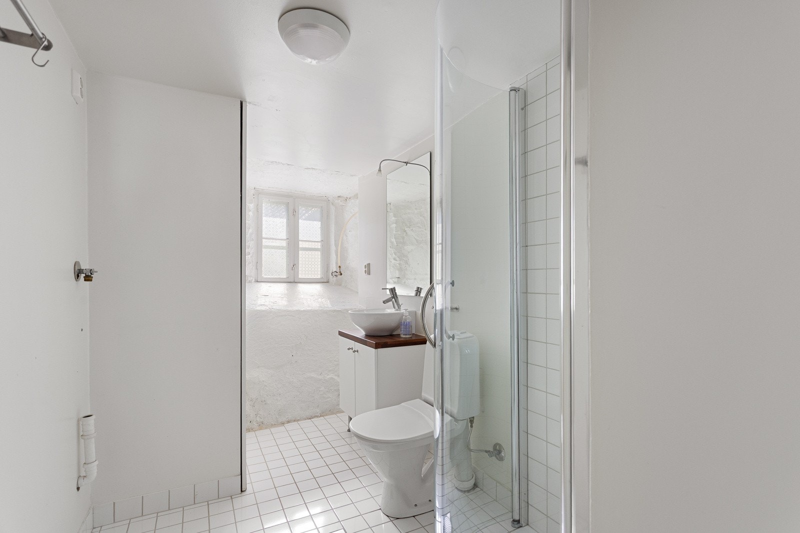 Badet i kjelleren er utstyrt med servant, toalett, dusjhjørne med svingbare glassdører og opplegg for vaskemaskin Galleribilde